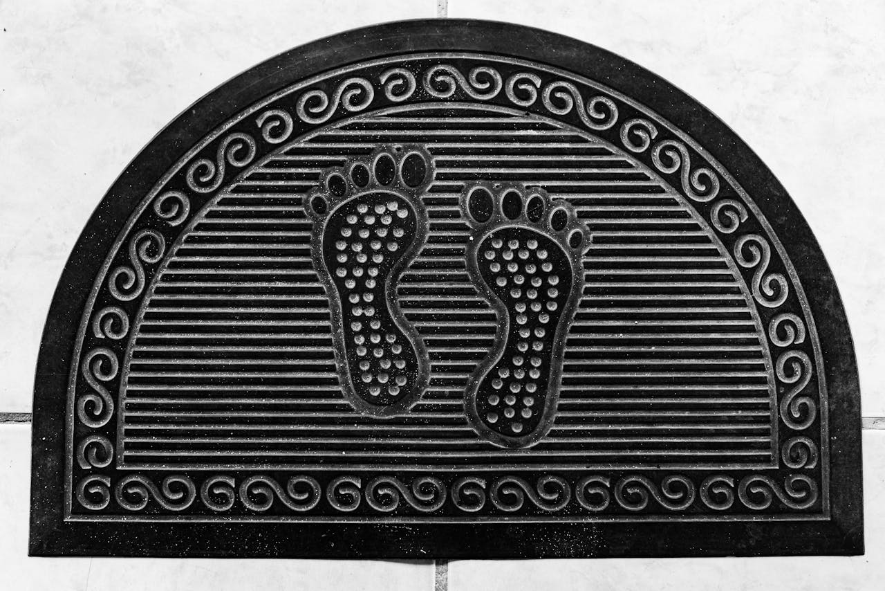 Black half-moon rubber door mat featuring embossed footprints, ideal for home entrances.